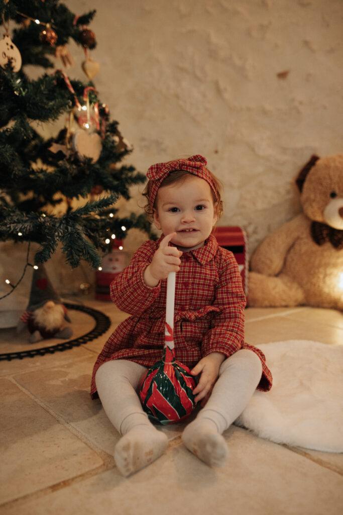 Petite fille assise devant le sapin, séance photo de Noël à Orléans