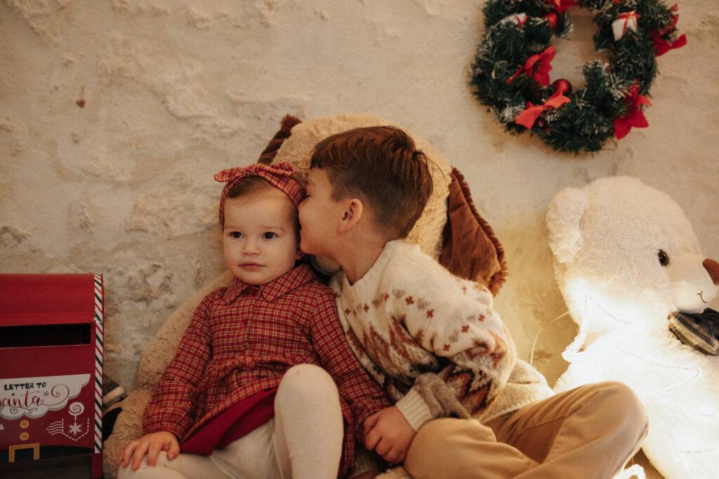 Bisou entre frère et sœur devant la couronne de Noël, séance photo à Orléans