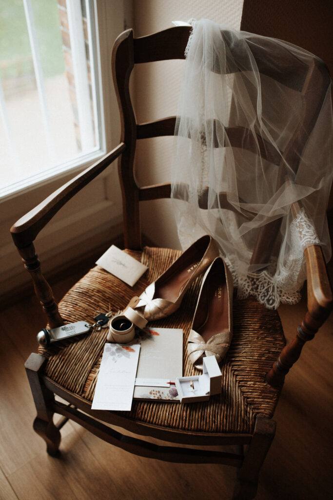Chaussures, voile et faire-part de la mariée posés sur une chaise ancienne au Domaine de Vaujoly