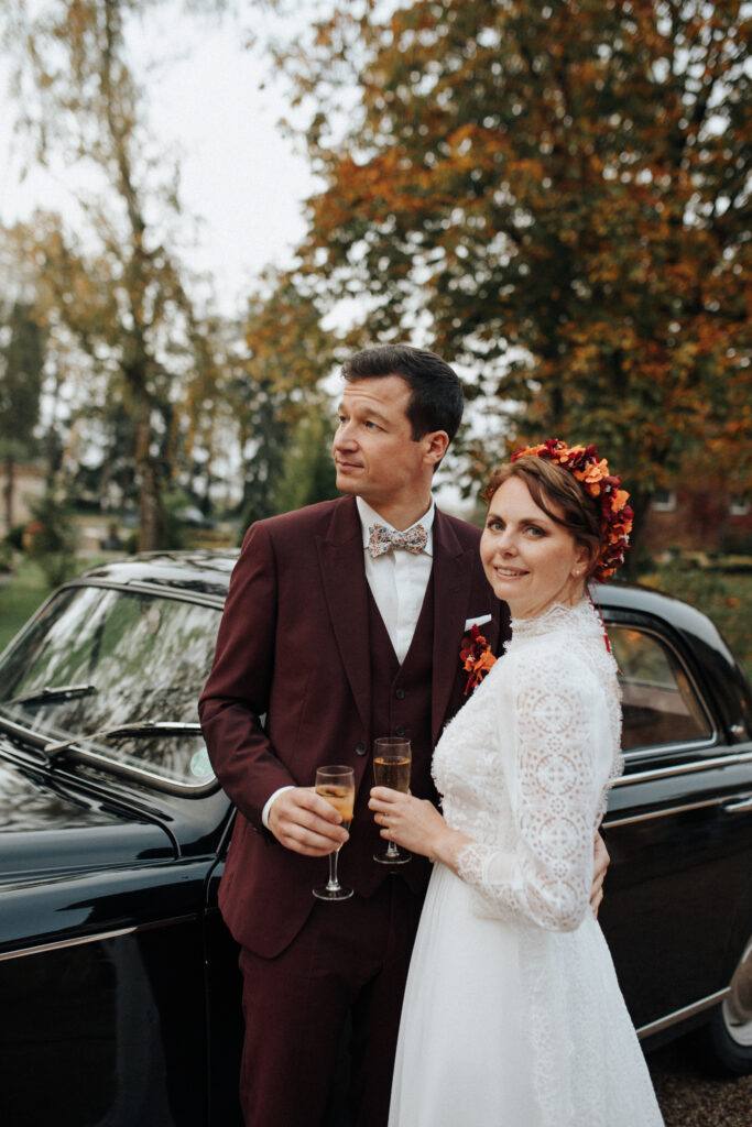 Les mariés trinquent devant une voiture ancienne Peugeot 403 au Domaine de Vaujoly