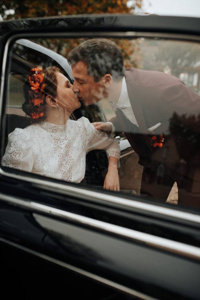 Baiser des mariés par la vitre de la voiture ancienne, mariage près de Chartres
