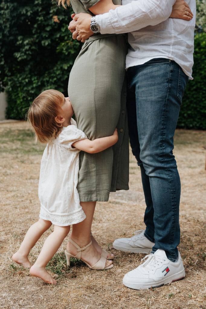 Petite fille qui s'accroche aux jambes de ses parents, séance photo famille