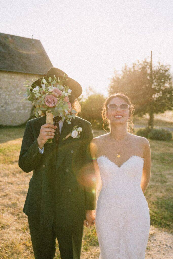 Le marié cache son visage derrière le bouquet, la mariée en lunettes de soleil, Domaine de la Volière