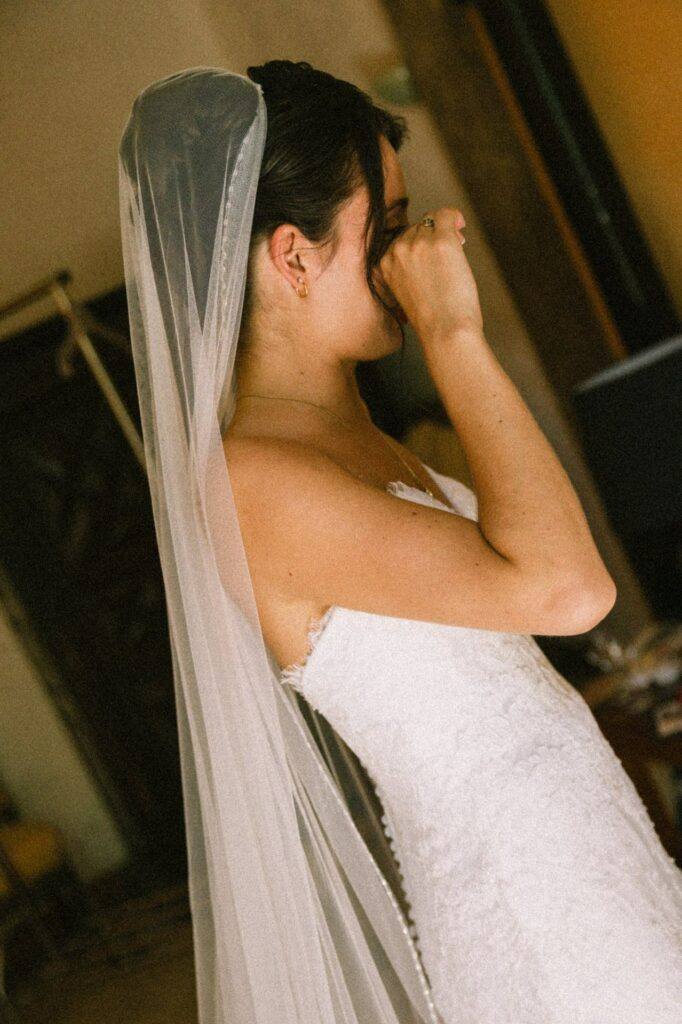 Portrait de la mariée émue sous son voile pendant les préparatifs au Domaine de la Volière