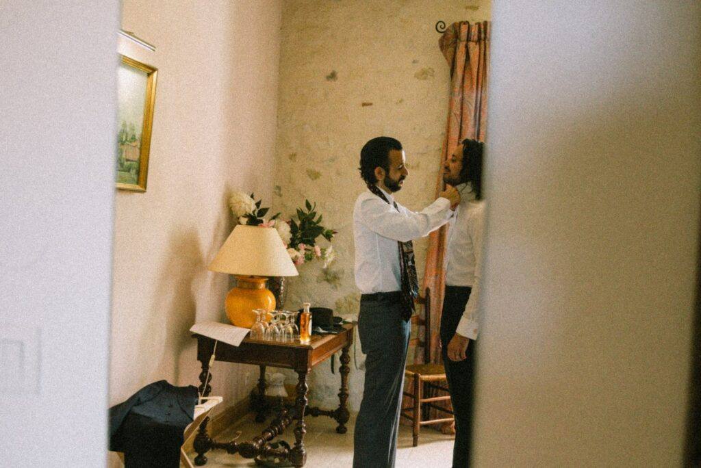 Le marié noue sa cravate à motifs pendant ses préparatifs au Domaine de la Volière