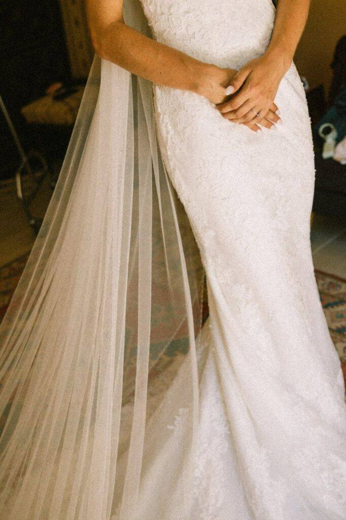 Robe de mariée en dentelle et voile pendant les préparatifs au Domaine de la Volière