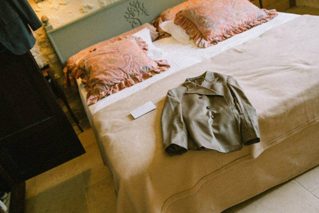 Veste verte du marié posée sur le lit pendant les préparatifs au Domaine de la Volière