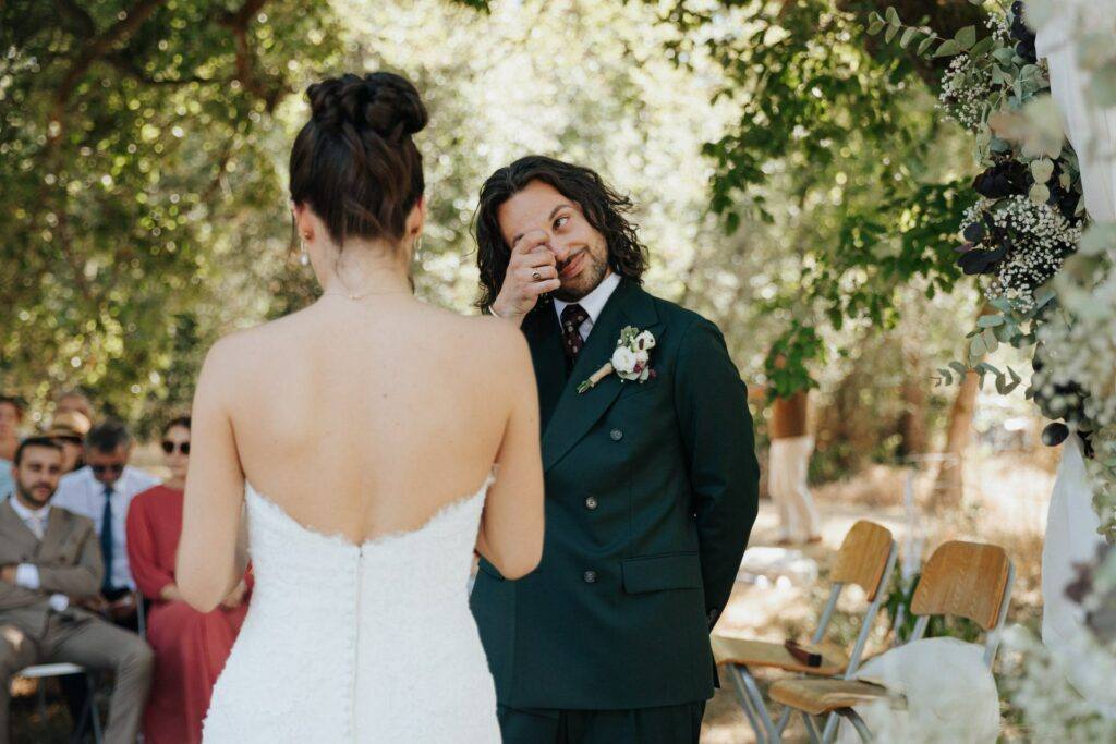 Le marié en costume vert essuie une larme pendant les vœux de la mariée, cérémonie laïque au Domaine de la Volière