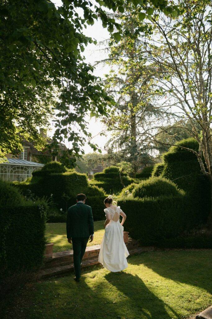 Les mariés s'éloignent dans les jardins topiaires du Manoir du Grand Courtoiseau à la lumière dorée