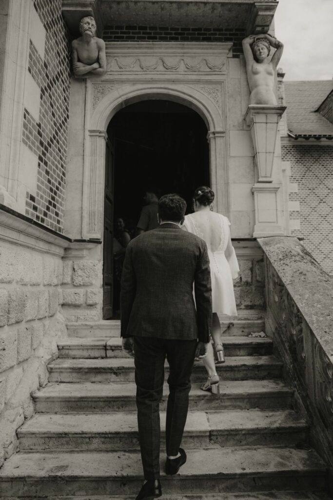 Les mariés montent l'escalier de l'Hôtel Groslot avant le mariage civil à Orléans, en noir et blanc