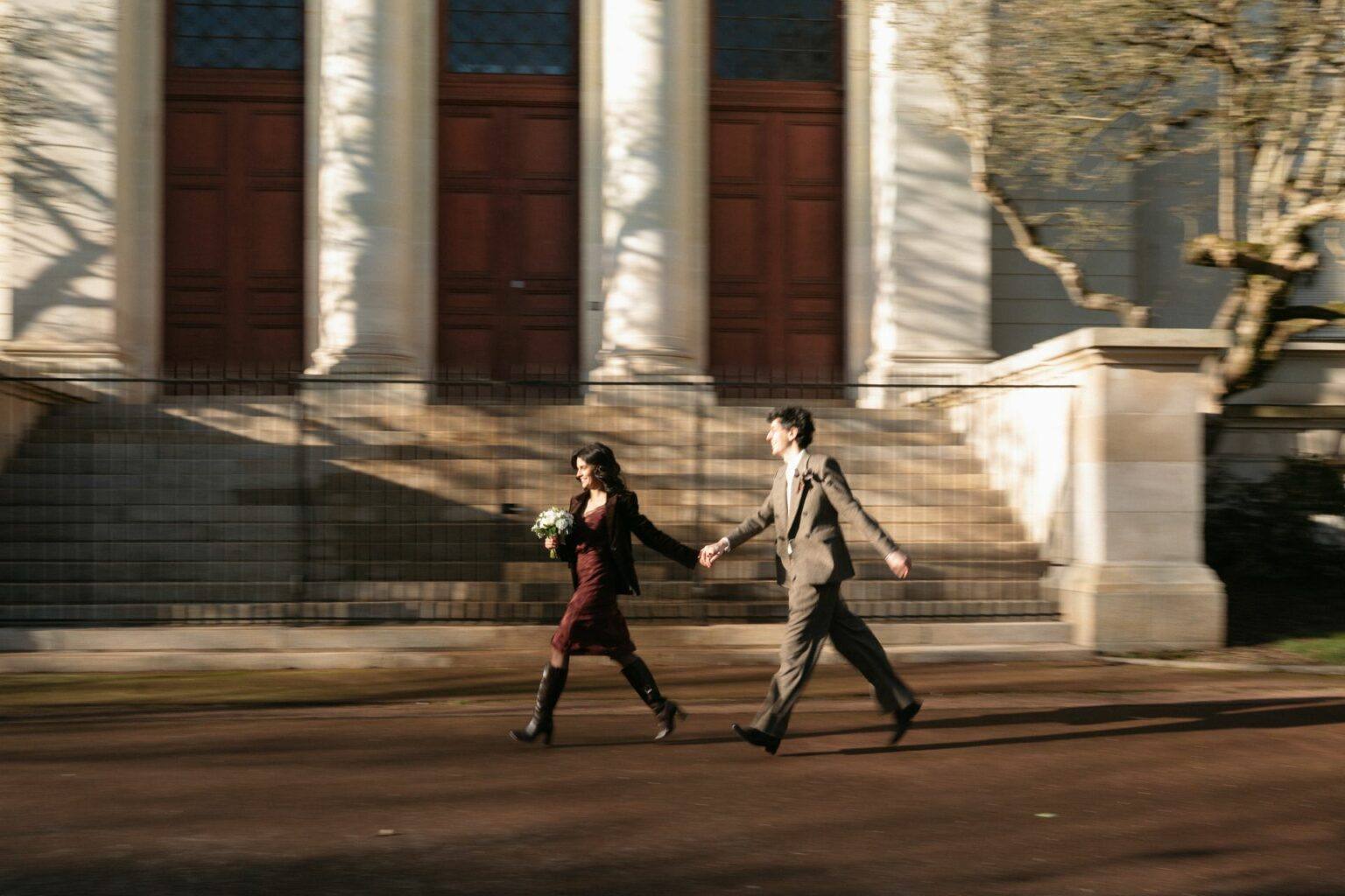 Jeunes mariés main dans la main devant un bâtiment à colonnes à Cholet, photographe de mariage Clara Valette