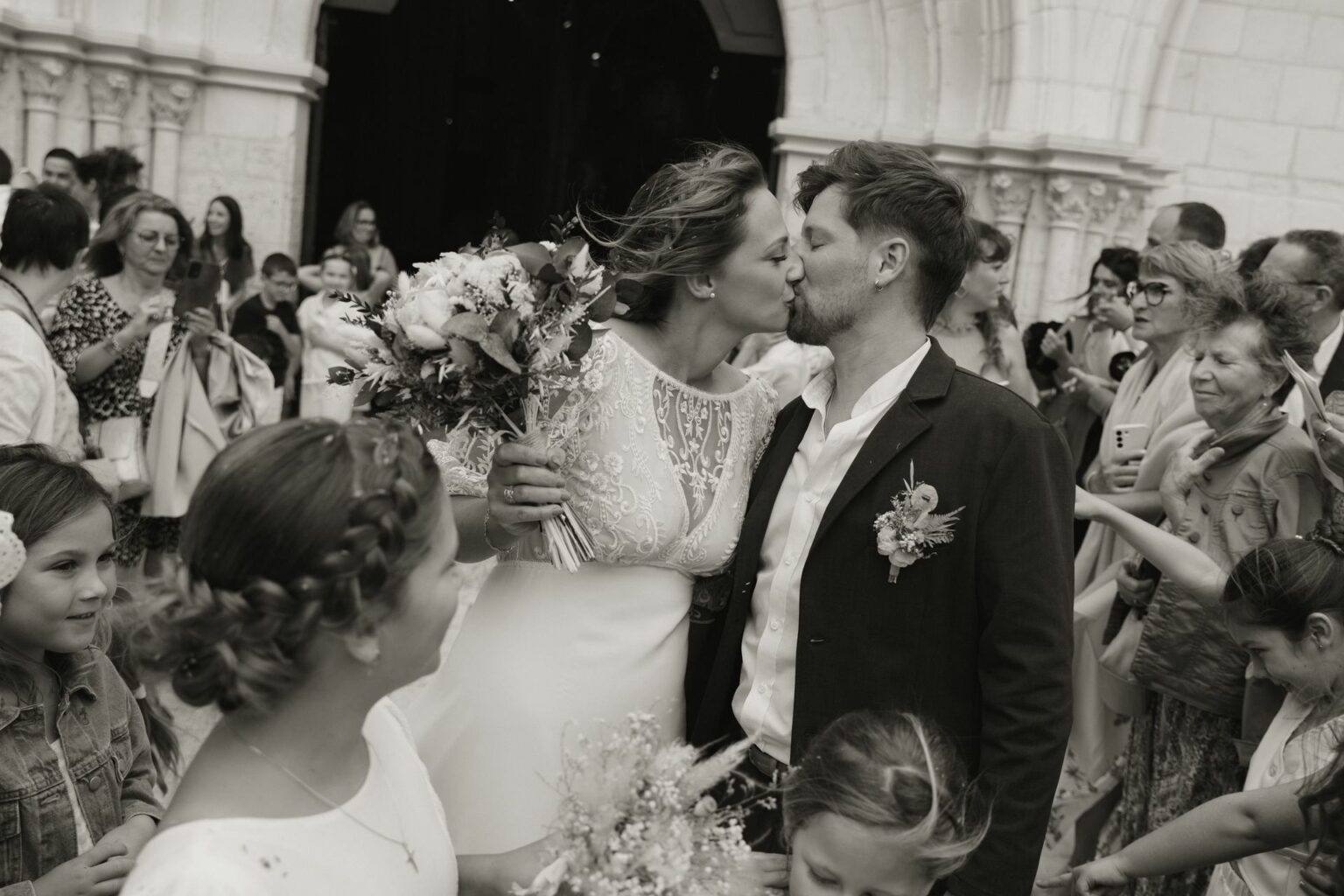 Baiser des mariés à la sortie de l'église de Romorantin-Lanthenay, mariage photographié par Clara Valette